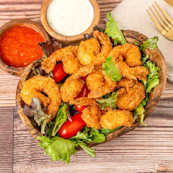 Crispy fried shrimp salad with cherry tomatoes and mixed greens, served with two dipping sauces.
