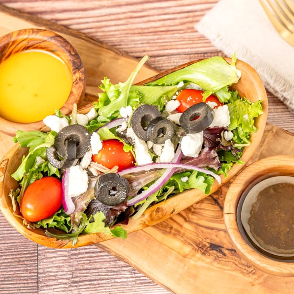 Fresh garden salad with feta, olives, tomatoes, and red onion, served with two dressings.