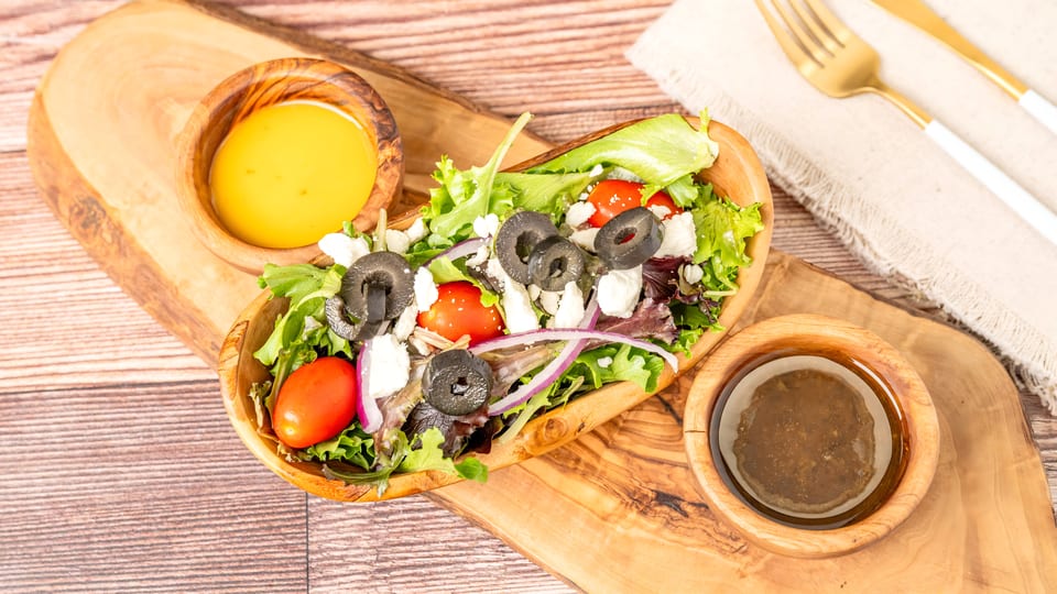 Fresh garden salad with feta, olives, tomatoes, and red onion, served with two dressings.