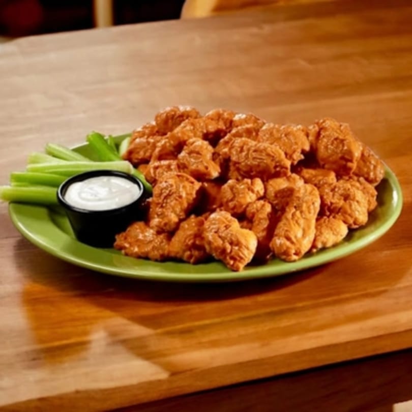 A green plate of Jax Fish Shrimp and Chicken's fried chicken bites, celery sticks, and ranch dip.