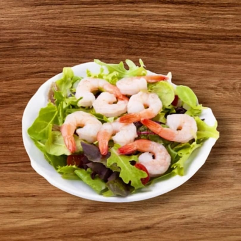 A fresh shrimp salad with mixed greens and cherry tomatoes on a white plate.